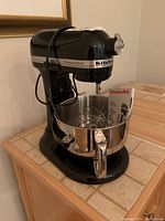 Front-angle view of onyx black KitchenAid mixer with bowl and manual in place