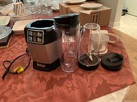 Ninja juicer base with blending cups and accessories on table