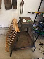 Photo showing metal outdoor fireplace positioned next to wooden foldable wood rack and hanging metal fire poker