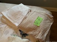 Folded white pillow sham and floral print neutral bedding underneath