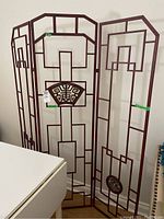 Front view of three-panel metal room divider screen with geometric cutout design and decorative motifs.