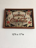 Full view of Coca-Cola wall clock showing wood frame, ornate decorative face, and clock hands.