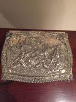 Top view showing detailed etched outdoor playful scene with figures on lid