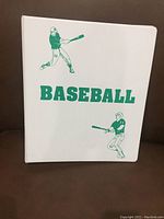 Front cover of white binder with green “BASEBALL” text and player silhouettes