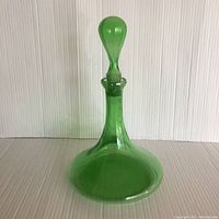 Side view of green blown glass wine decanter showing shape and stopper