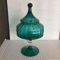 Full view of vintage Empoli blue-green apothecary jar with steeple tip lid and clear glass stem on blue-green base