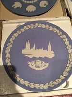 Image of the Wedgwood Christmas 1974 commemorative ceramic plate with The House of Parliament relief design, showing lavender background and white decorative border with text.