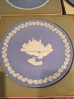 Close-up showing the full front view of the Wedgwood Christmas 1973 Tower of London collector plate with its blue jasperware background and white relief design including the laurel wreath border, the Tower of London, and a swan in water beneath it.