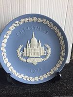 Front view of blue Wedgwood jasperware plate with white relief of St Pauls Cathedral, lettering 'Christmas 1972' and decorative border.