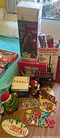 Photo showing boxed fiber optic Christmas tree, several rolls of wrapping paper, boxed Hoover vacuum cleaner, and holiday plaques arranged on table.
