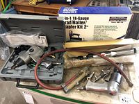 Overview of pneumatic tools including air ratchet wrench, pneumatic fittings, hoses, and boxed brad nailer/stapler kit.