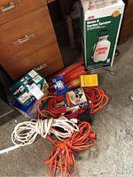Photo of lot including Ace Home & Garden Sprayer box, several extension cords coiled on floor, and other items in garage.