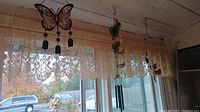 Wind chimes with animal and butterfly designs hanging on window rod