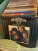 Photo showing The Oak Ridge Boys Greatest Hits vinyl record among a stack of records inside a green plastic tote.
