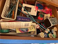 Overview of sewing notions in bins including threads, pins, needles, scissors, and containers.