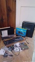 Royal crosscut shredder, HP desktop tower, new keyboard in packaging, cables, and Linksys router box displayed on floor.