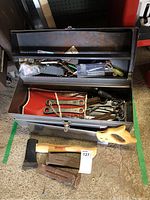 Open Vermont American metal toolbox showing assorted tools inside including wrenches, screwdrivers, and clips with Razorback axe and metal pry bars placed in front.