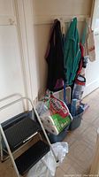 Photo of cleaning items and jackets hung on wall hooks with bucket and mop beside them