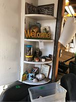 Corner shelf with multiple shelves holding bird figurines, decorative signs, ceramic vases, and other small decorative objects