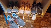 Four pairs of women's athletic shoes on shelf in a row, various colors and styles