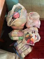Photo showing multiple skeins of yarn, crochet hooks, and a crochet instructional book in bags.