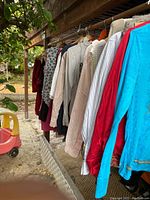 Clothes hanging on rack outside, various women's garments visible including shirts and jackets.