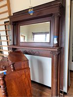 Full view showing the entire wooden mantel with mirror, mounted retail style.