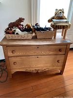 Full view of vintage wooden dresser with two drawers, with baskets and plush tiger toy on top, displaying overall condition and style.