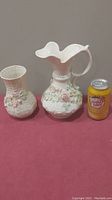 Two Belleek Irish porcelain vases side by side with a soda can for scale, showing floral details and sizes.