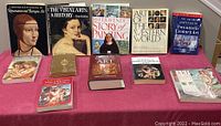 Full view of 12 art history books laid out on pink cloth, various sizes, titles visible, covers showing wear.