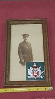 Full frontal view of framed sepia military officer photo with attached 2nd Infantry badge and measuring tape below