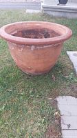 Side view of the large terracotta planter on grass, showing wide rim and exterior wear.