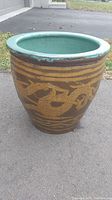 Full view of the large brown ceramic planter with gold dragon designs and turquoise glazed interior, showing the shape and size.