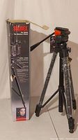 Full view of the tripod standing beside its original box showing Solidex branding and model details