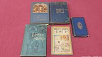 Five old religious hardcover books on pink surface including 'Patriarchs and Prophets', 'The Story of David', and others.