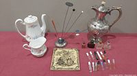 Full lot photo showing all items including Paragon china teapot and creamer, silver coffee pot, trivet, hat pin holder with pins, and perfume bottles.
