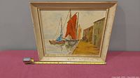 Full view of framed oil painting showing dock, sailboats, and buildings with red and blue sails, signed H.D. McLeod 1967.