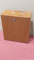 Wooden carrying case closed with handle on top and Tasco Deluxe label