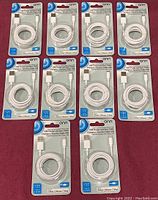 Lot of ten Onn branded USB charge and sync cables in original sealed packaging, laid out on a flat red surface.