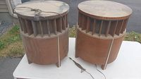 Pair of cylindrical retro speakers on a white surface outdoors, visible heavy dust on all surfaces and cords lying untidily.