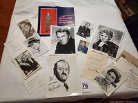 Group photo of vintage autographed celebrity photos and letters laid out on a white surface