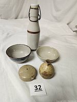 Photo showing all items arranged on white cloth background, Saki jar, two bowls, incense holder, ink well.