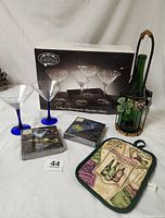Photo of 5-piece Metropolitan Martini glasses in original box, 2 SKYY vodka glasses, metal wine bottle caddy with grape leaves design, green decorative wine bottle with grape decoupage, two packages of Martini Cypress Home cocktail napkins, and a wine-themed pot holder.
