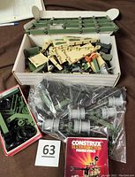 Box with green beams, beige panels with camouflage design, black wheels, and gray connectors, showing set contents