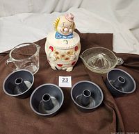 Full view of the set including measuring cup, ceramic clown cookie jar, four angel food pans, and glass hand juicer