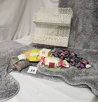 Photo showing all items including gray rugs, white metal storage shelf, tea trays, soap dish, soap bar, heating bag, and lavender sachet.