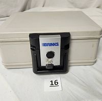Front view of Brinks lock box showing handle, lock panel with key inserted, and logo.