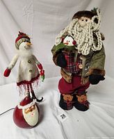 Photo showing the three holiday items: plush Santa holding snowman stocking, snow lady figurine, and Meadowbrooke gourd Santa head with light-up feature.