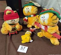 Five vintage Garfield plushes including three winter-themed 7-9 inch figures and two small clip-ons, displayed on dark fabric with lot number.