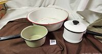 Photo showing all three enamelware items: small white pot with black handle and lid, avocado green sauce pot, large white dish pan with red rim.